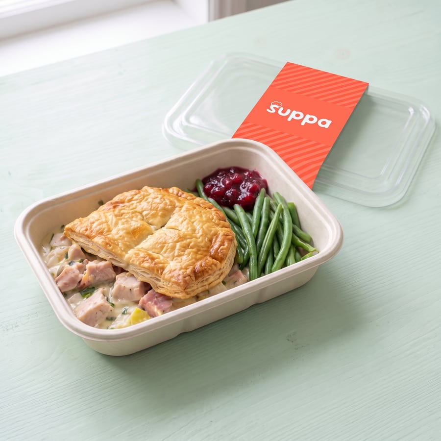 Boxing Day Pie in an open Suppa tray, with its clear lid and coral sleeve set beside it