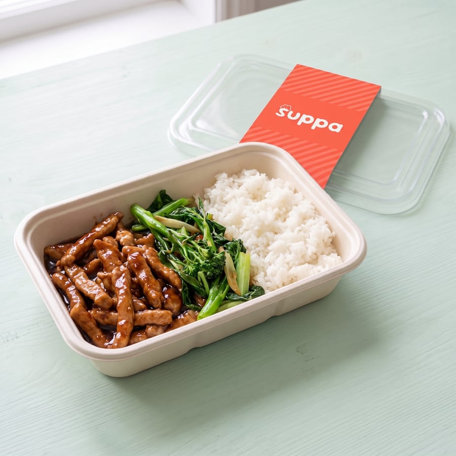 Honey garlic pork in an open Suppa tray, with its clear lid and coral sleeve set beside it