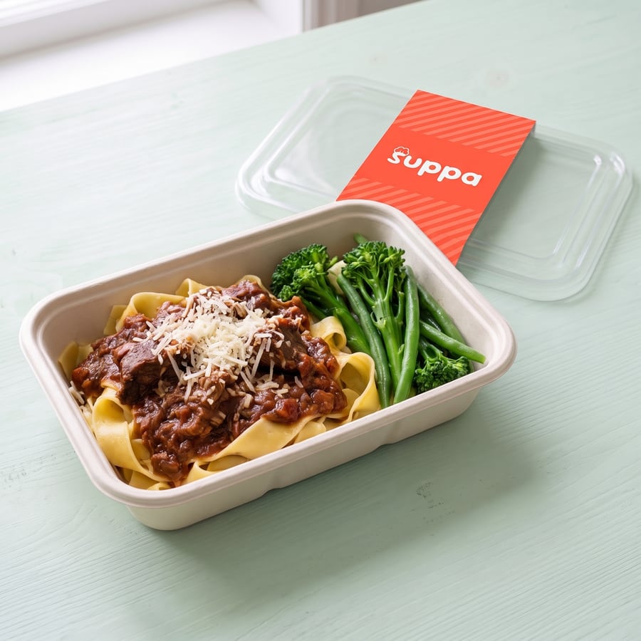 Slow-cooked beef ragu in an open Suppa tray, with its clear lid and coral sleeve set beside it