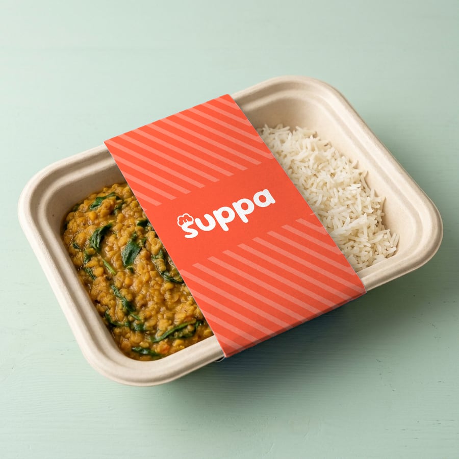 Red lentil and spinach dal packed in a Suppa tray with a orange striped sleeve